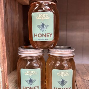 Three jars of honey are sitting on a shelf.