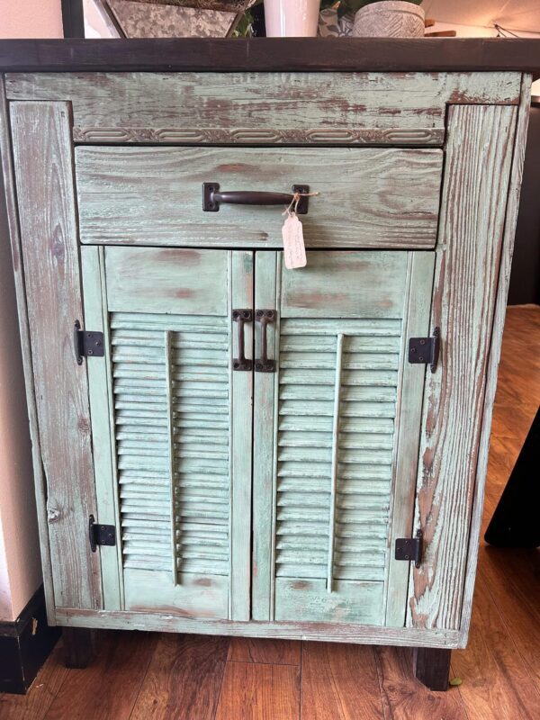 A cabinet with shutters and a drawer.