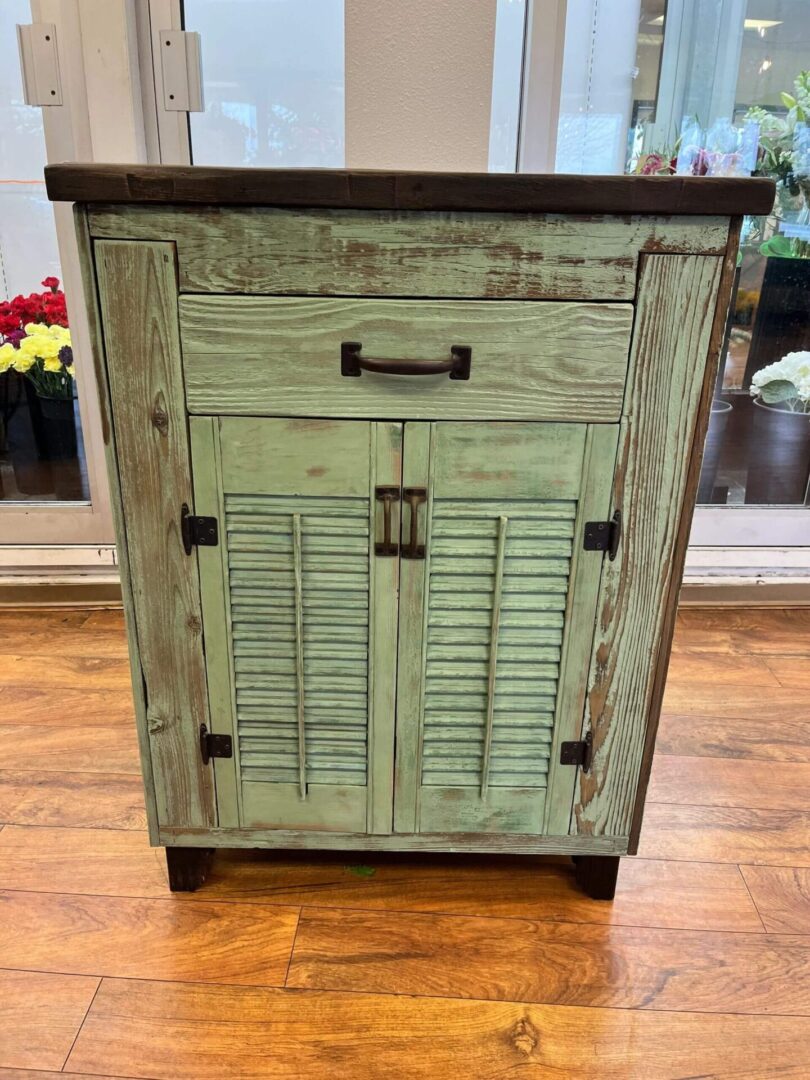 A green cabinet with shutters on the doors.