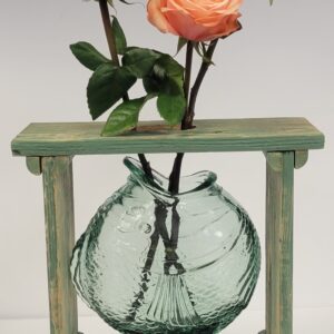 A vase with flowers in it on top of a wooden stand.
