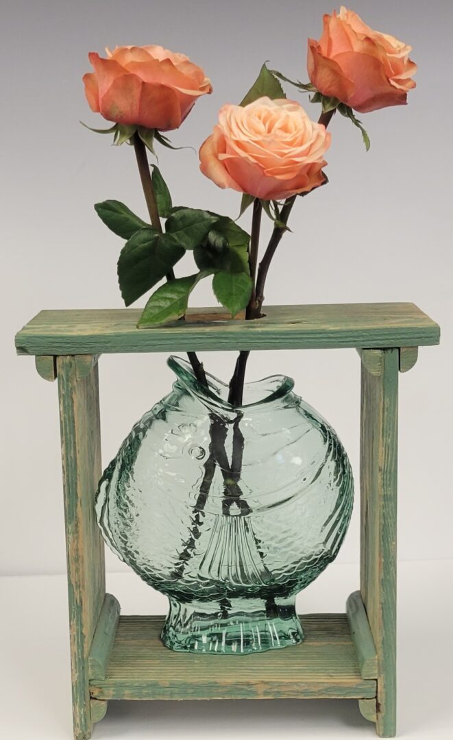 A vase with flowers in it on top of a wooden stand.