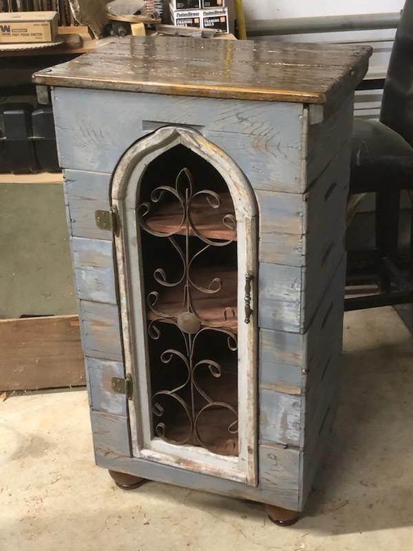 A small cabinet with a metal door and iron work.